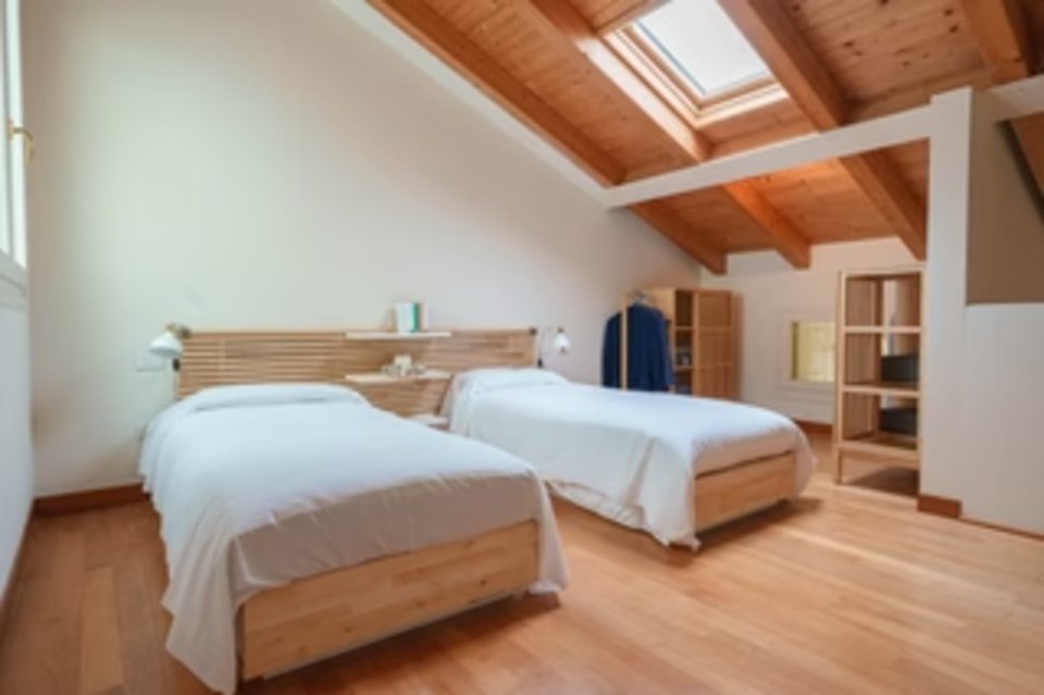 A bright twin bedroom inside the renovated barchesse apartments at H-FARM Marina
